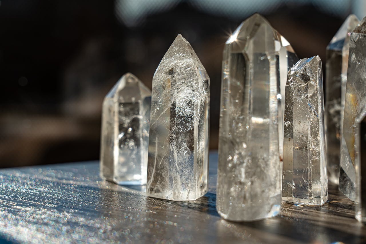 A detailed close-up of clear quartz crystals reflecting light with a blurred background.