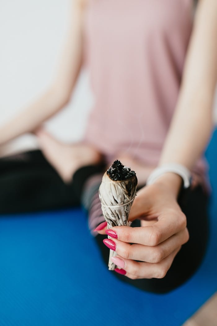 Početna 6 faceless woman practicing ardha padmasana exercise with burning natural white sage incense in hand 4498318